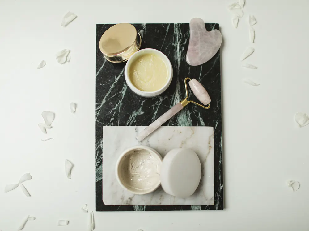 Skincare ritual with creams and a gua sha on marble